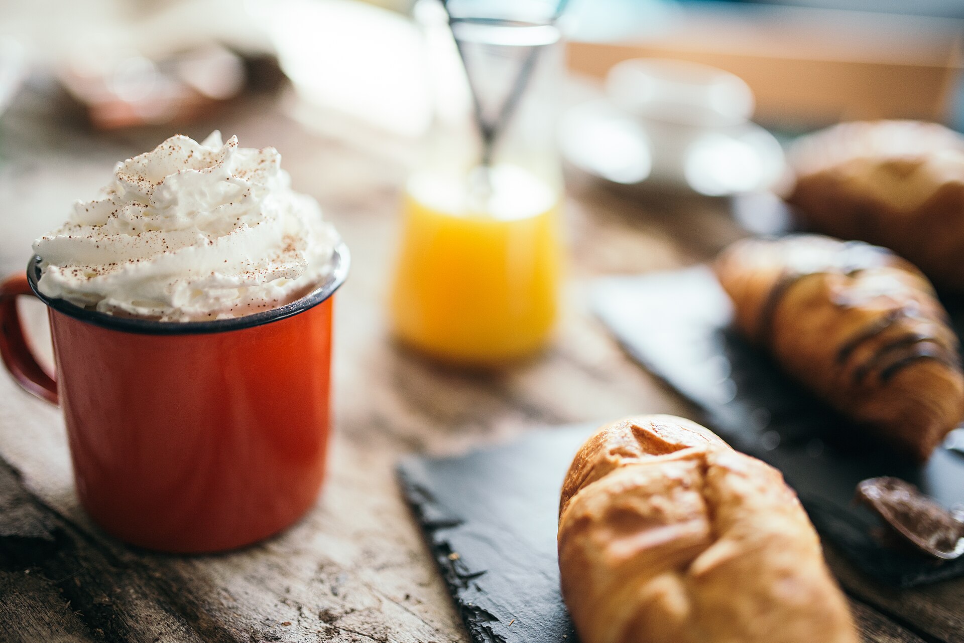 Heißgetränk mit Sahne und Gebäck auf einem Cafétisch